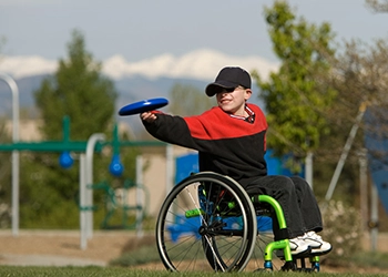 boy playing frisbee in a wheelchair.